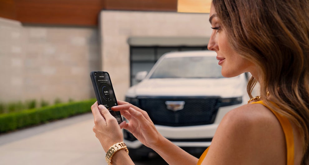 lady checking her mobile with a Cadillac vehicle background | Palmen Cadillac in Kenosha WI